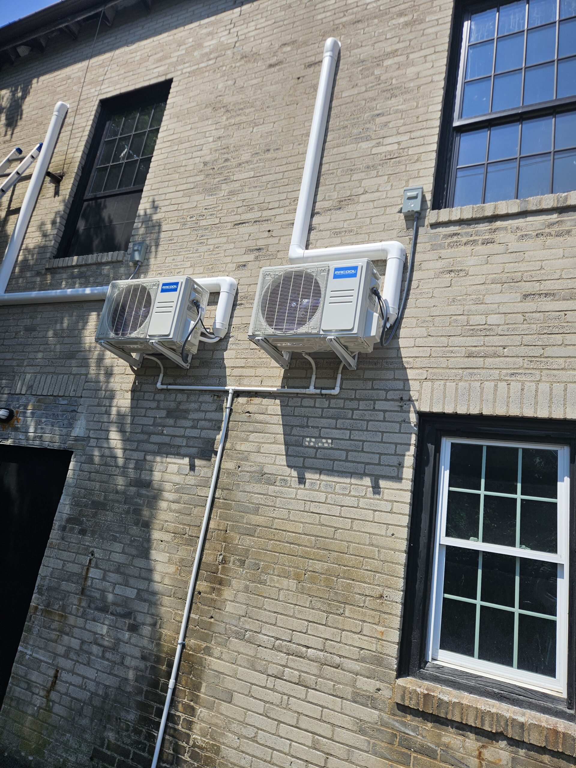 MRCOOL condensers mounted on the brick exterior of the church with line-set covers running down the wall