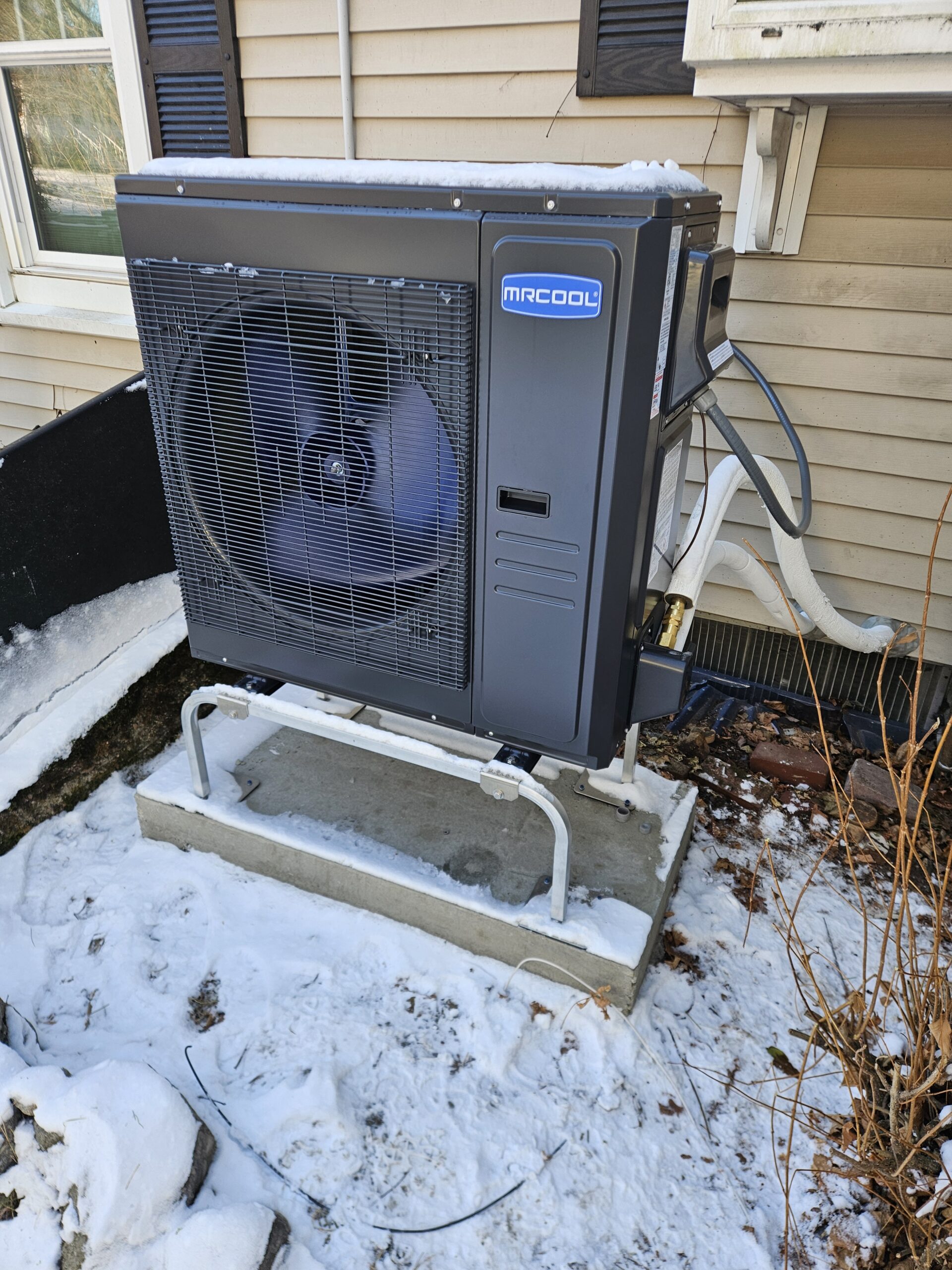 MRCOOL heat pump running through a New England winter with snow on the cabinet