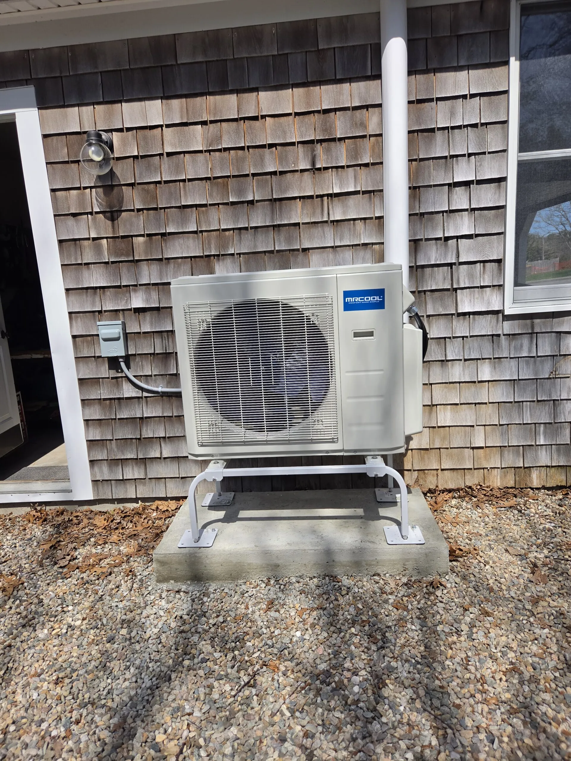 MRCOOL heat pump condenser installed beside a cedar-shingled Massachusetts home