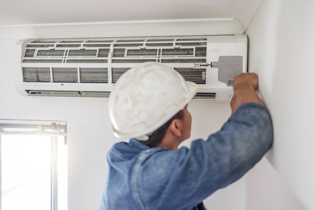 Technician mounting a ductless mini-split indoor unit on a bedroom wall for a Marlborough, MA heat pump installation