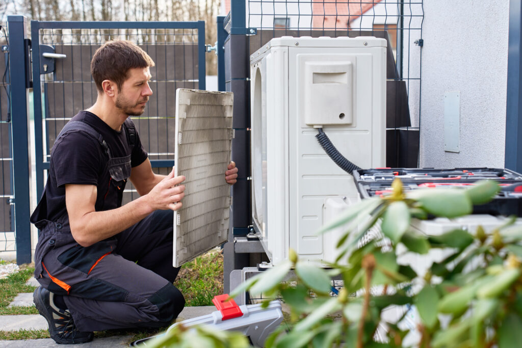 Technician checking an outdoor heat pump unit at a Taunton-area home on TMLP power